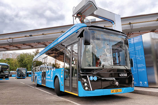 MOSCOW, RUSSIA - CIRCA JULY, 2019: Modern electric city bus of Moscow public transport system charging battery at charge station for hybrid vehicle on street of russian capital front wide view